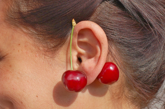 Red cherries on woman ear